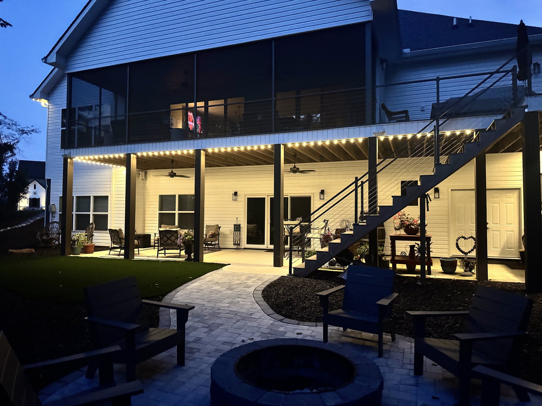 Covered patio and firepit seating area lit by EverLume permanent lighting