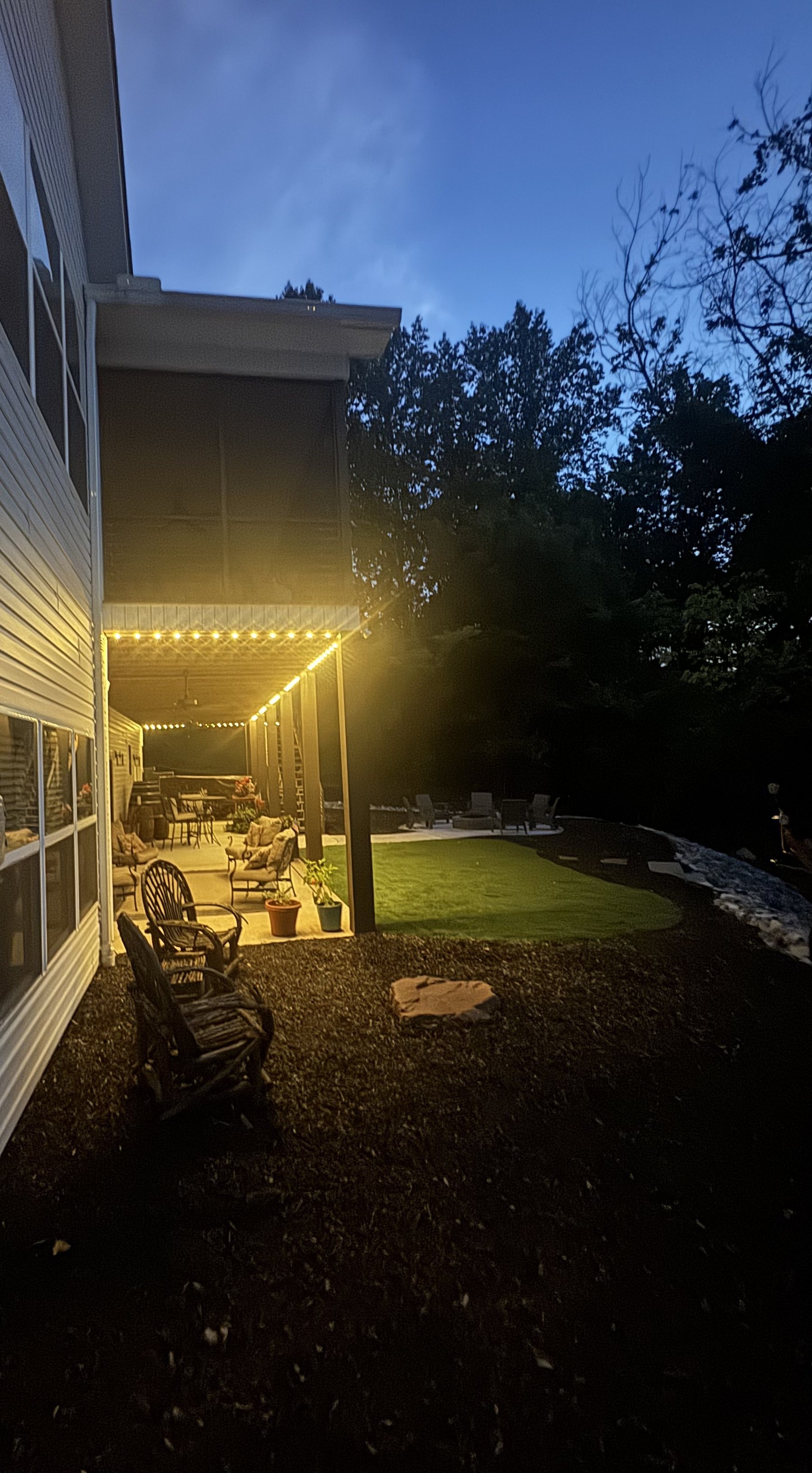 Screened porch and covered patio lit warm white at dusk
